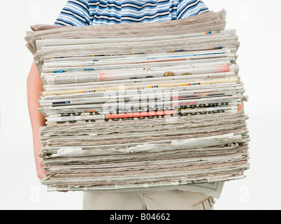 Boy carrying a stack of newspapers Stock Photo