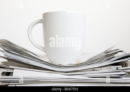 Cup on stack of newspapers Stock Photo