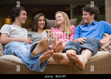 Teenagers sat on a sofa talking Stock Photo