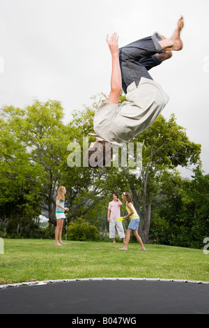 A teenage boy doing somersaults on a trampoline