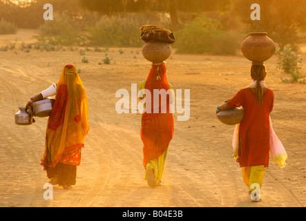 Three Rajasthani ladies wearing traditional village costumes collecting water Stock Photo