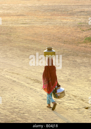 Young girl fetching water and balancing a container on her head, Near Jaisalmer, Rajasthan, India Stock Photo