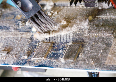 Inside a computer showing dust built up on the components. a small brush is used to clean this graphics card. Stock Photo