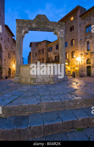 Well in Piazza della Cisterna at dusk in the historic old town centre of San Gimignano, a UNESCO World Heritage Site Stock Photo