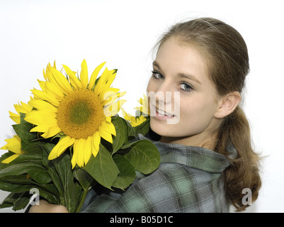 young natural woman with ponytail and karo shirt with a bunch of sunflowers in her arms Stock Photo