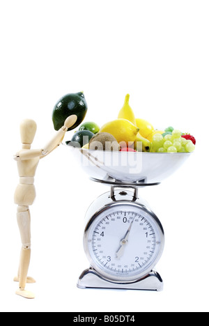 jointed doll taking fruit from scale Stock Photo