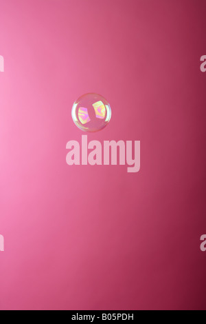 single soap bubble against a pink studio background. Stock Photo