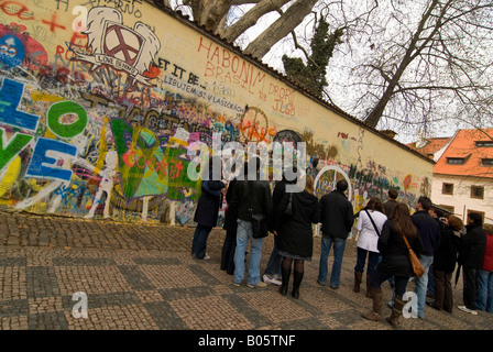 Horizontal wide angle of tourists writing a message on the Lennon Peace Wall in the Lesser Quarter 'Mala Strana'. Stock Photo