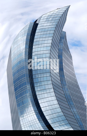 Distorted futuristic corporate building with glass walls reflecting clouds Stock Photo