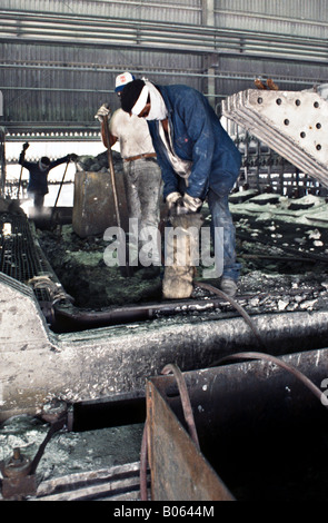 Workers digging out pot lining in primary aluminum reduction facility with jack hammer in Venezuela Stock Photo