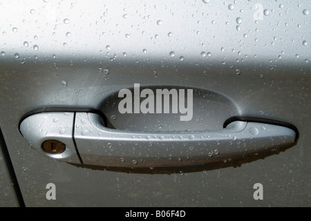 Car Door Handle Covered in Raindrops on Metallic Surface Stock Photo