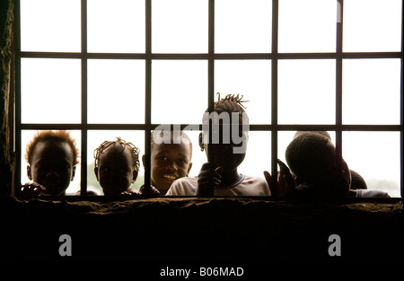 Children looking through the bars of a schoolroom window of a village school in the Gambia, West Africa Stock Photo