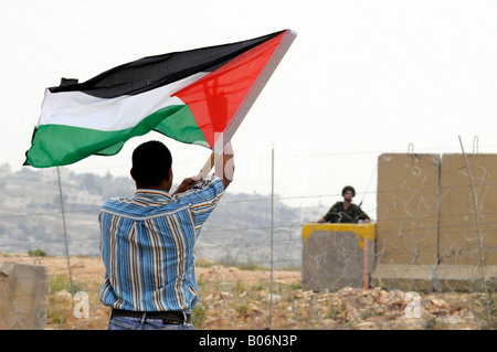 A young man raising the Palestinian flag during a protest against Israeli occupation in the village of Bilin, Palestine. Stock Photo