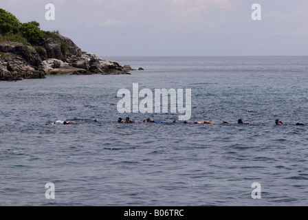 People wearing life jackets and snorkling equipment being towed with a rope behind a longtail boat Stock Photo