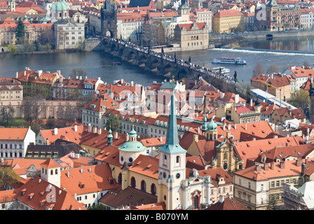 Horizontal wide angle across the rooftops of Mala Strana 'Lesser Quarter' and Karluv Most Charles Bridge on a sunny day. Stock Photo