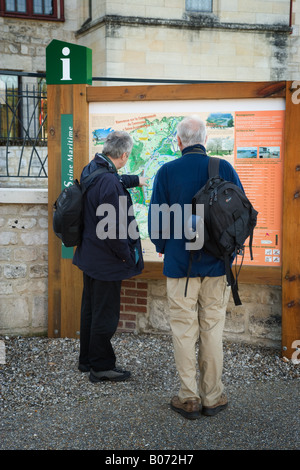 Two English tourists looking at a town map on a tourist information notice outside the Abbaye de Jumieges. Stock Photo