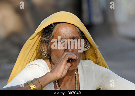 Close-up of an old tribal woman smoking bidi, an Indian handmade cigarette made of tobacco or beedi leaves. Bhil tribe Stock Photo