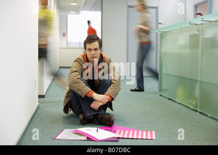 Young man sitting on a corridor floor Stock Photo