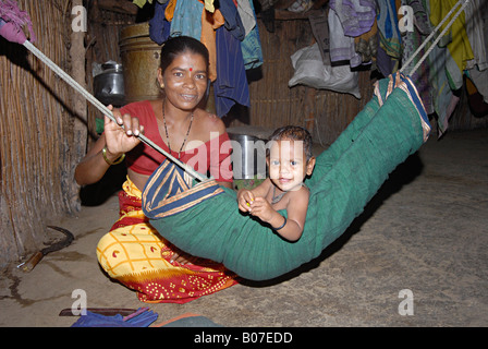 Mother swinging her baby in a hammock. Katkari tribe Stock Photo