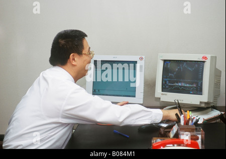 Asian Chinese Businessman Looking At Graph On Computer Stock Photo