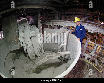 Man standing next to large machine where old waste paper is shredded and mixed with water in recycling plant Stock Photo