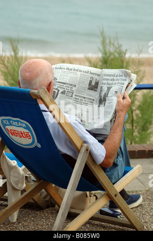 senior man reading newspaper on the seafront at Eastbourne, East Sussex, England, UK Stock Photo