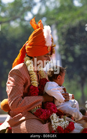 India Ahmedabad Gujerat wedding procession groom on horseback with child in street Stock Photo