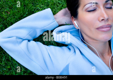 Woman lying on the grass and listening to music