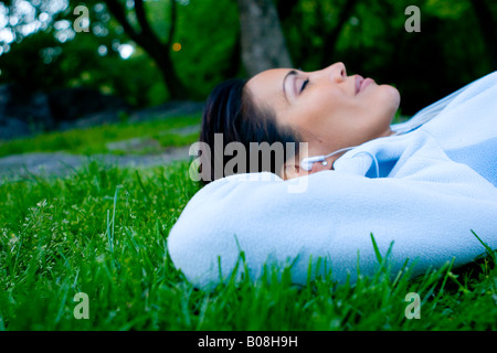 Woman lying on the grass and listening to music
