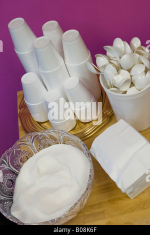 Styrofoam cups plastic spoons paper napkins and a bowl of sugar laying on a wooden table Location Released Stock Photo