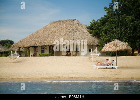 Thatched palapas, cabana and lounge chairs on beach, viewed from Caribbean Sea, Jaguar Reef Lodge, Hopkins, Stann Creek District Stock Photo