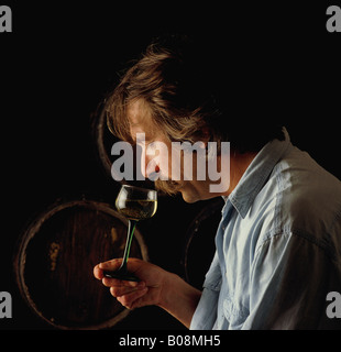 Man in wine cellar tasting glass of wine side view winetasting Stock Photo