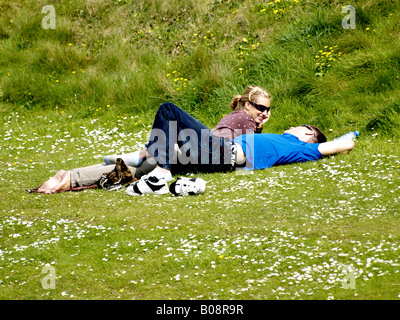 Young happy couple laying on the grass surrounded by daisies Stock Photo