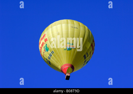 Ascending yellow hot air balloon in a blue sky, Bad Wiessee, Upper Bavaria, Bavaria, Germany Stock Photo