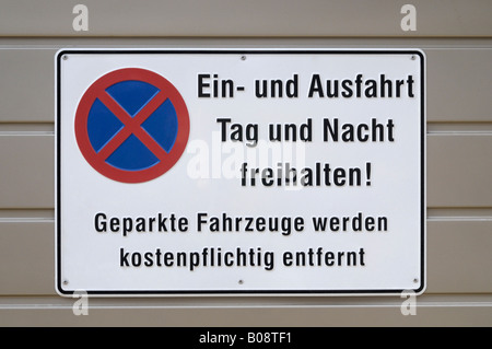 No parking sign, "Ein- und Ausfahrt Tag und Nacht freihalten! Geparkte Fahrzeuge werden kostenpflichtig abgeschleppt" (Keep ent Stock Photo
