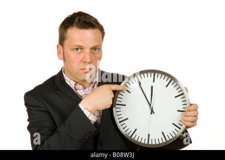 40-year-old businessman pointing at a clock, time is 5 to 12 Stock Photo