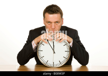 40-year-old businessman leaning on a clock, time is 5 to 12 Stock Photo