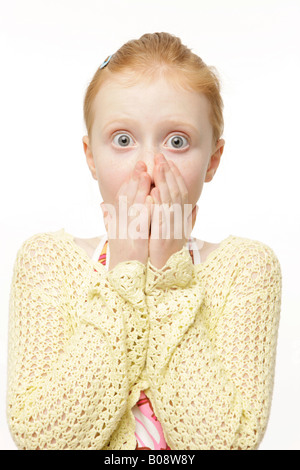 Redheaded 8-year-old girl wearing a yellow knit sweater, jumper, looking shocked Stock Photo