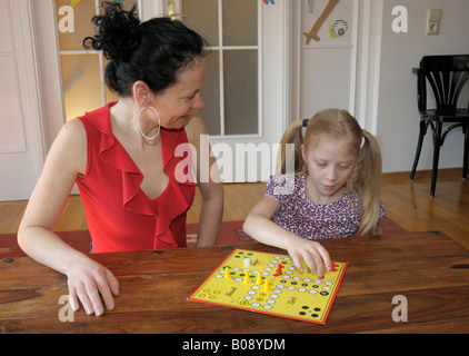 Mother with child, 10 years old, playing Ludo board game Stock Photo