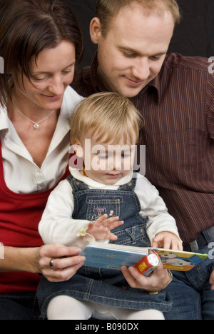 family portrait, parents with baby reading Stock Photo