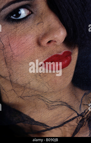 Netted black veil covering a young woman's face, widow Stock Photo