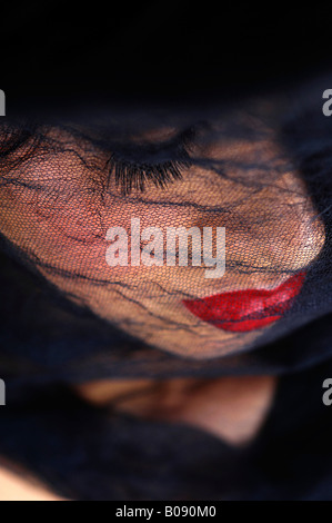 Netted black veil covering a young woman's face, widow Stock Photo