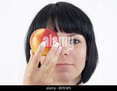 black-haired women holding an apple in front of her face Stock Photo