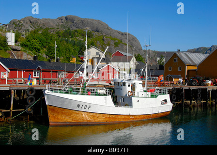 Wooden fishing boat tied up to a jetty and red wooden 'rorbu' houses in Nusfjord, Lofoten Archipelago, Norway, Scandinavia Stock Photo