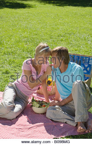 http://l450v.alamy.com/450v/b098mg/young-couple-sitting-on-picnic-blancket-woman-feeding-man-with-radish-b098mg.jpg