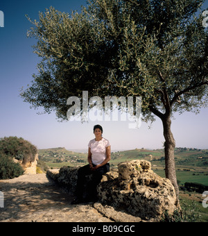Woman sitting in the shade of an Olive tree Sicily. Stock Photo