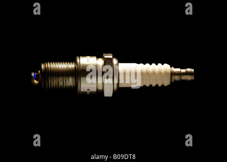A used spark plug with a real spark jumping between the electrodes Stock Photo