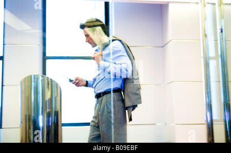 Businessman walking through hallway dialing cellphone Stock Photo