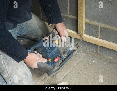 builder with drill fitting battens to an internal wall Stock Photo