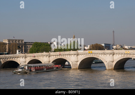 The Pont Neuf across the river Seine in Paris with a tourist boat passing below Stock Photo